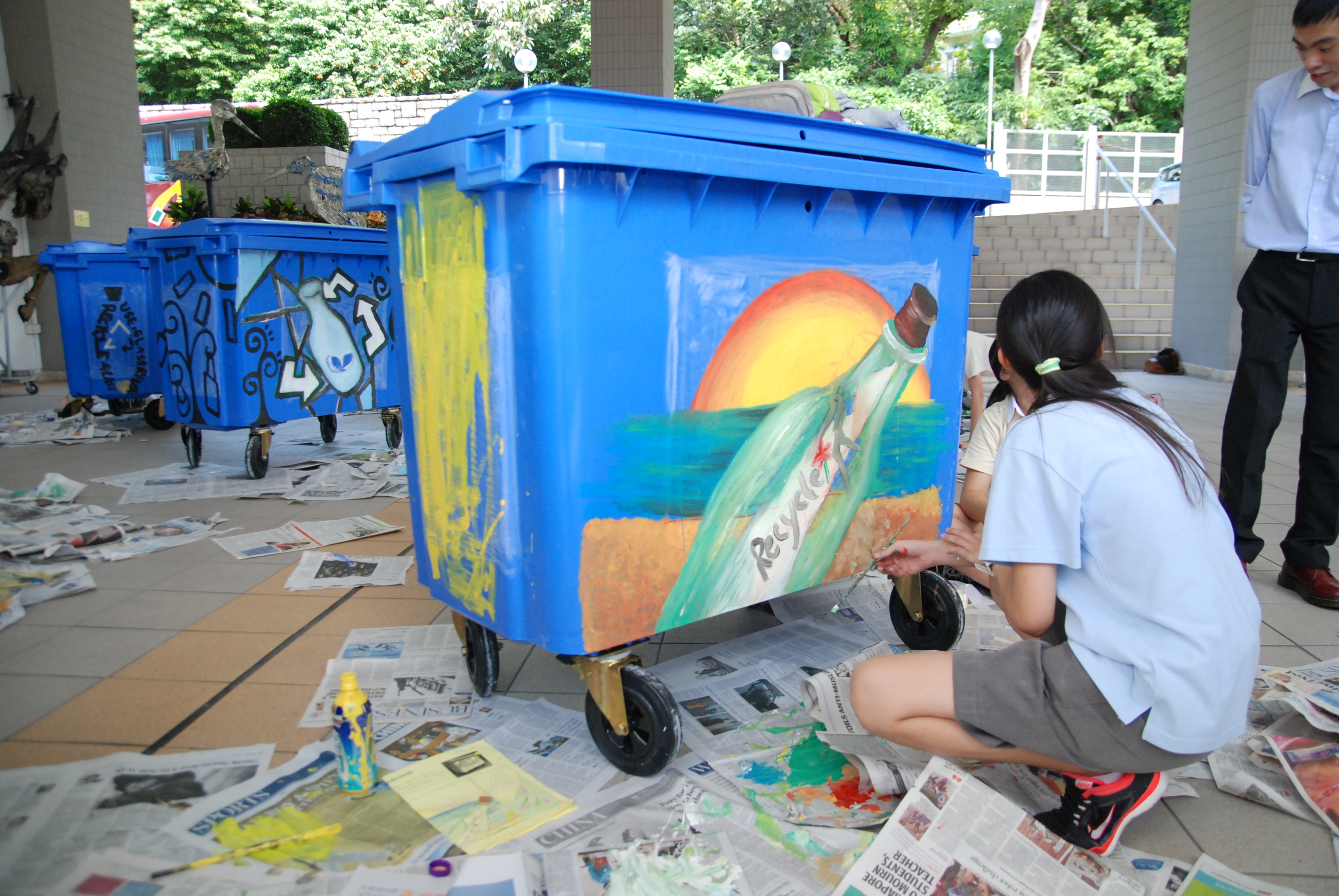 Students painting on glass recycling bins